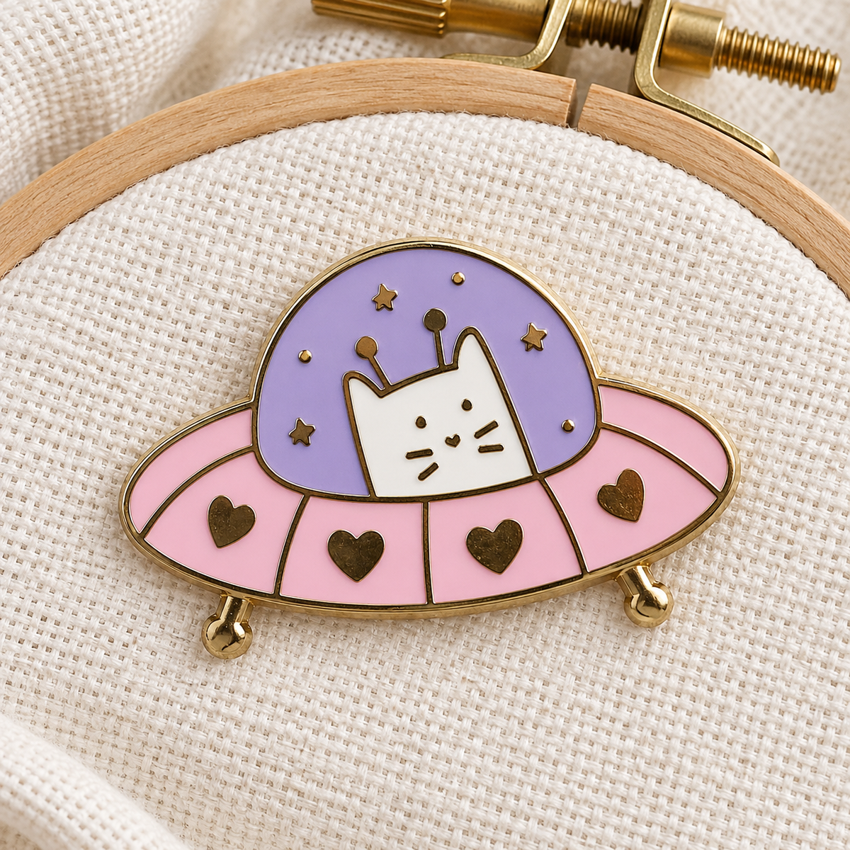 UFO Frank Needle Minder on an embroidery hoop, white cat in a pink and purple UFO with gold hearts