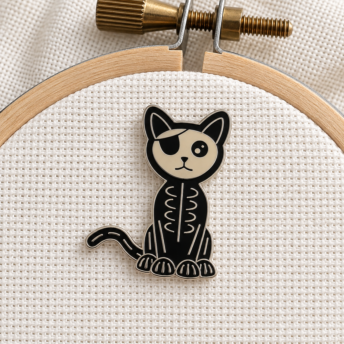 Skeleton Cat Needle Minder on an embroidery hoop, pirate skeleton cat with an eyepatch, gold finish
