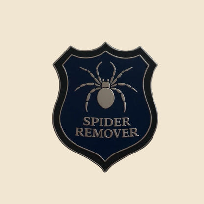 Spider remover second-grade enamel pin on a cream background