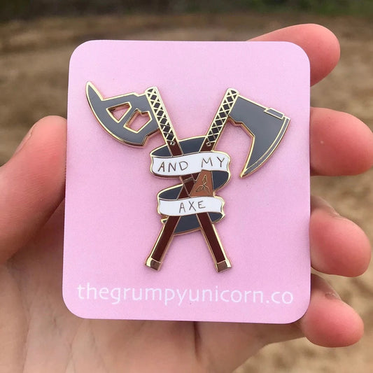 And My Axe pin on pink Grumpy Unicorn backing card held in hand outdoors