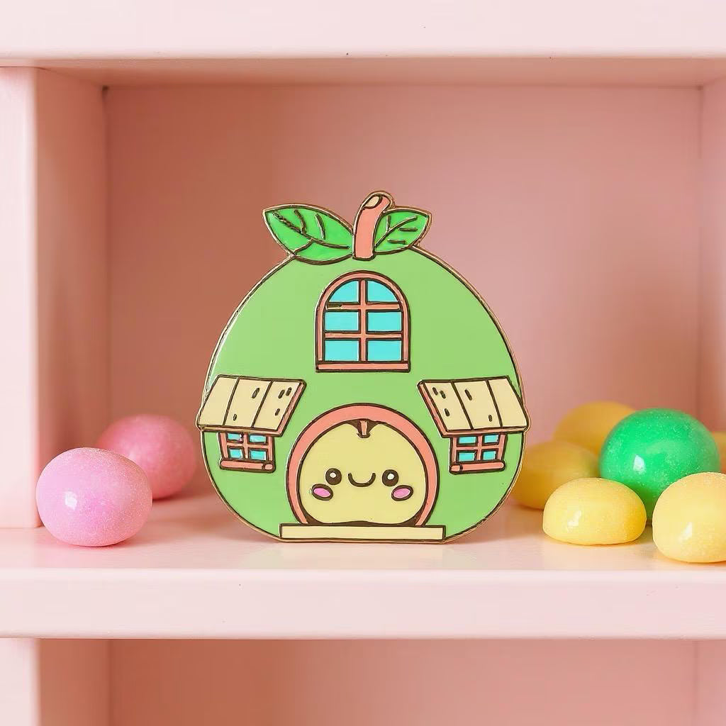 Apple House pin — kawaii green apple-shaped house with windows and smiling apple at the door, on pink shelf with gumballs