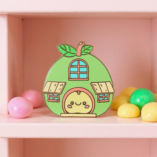 Apple House pin — kawaii green apple-shaped house with windows and smiling apple at the door, on pink shelf with gumballs