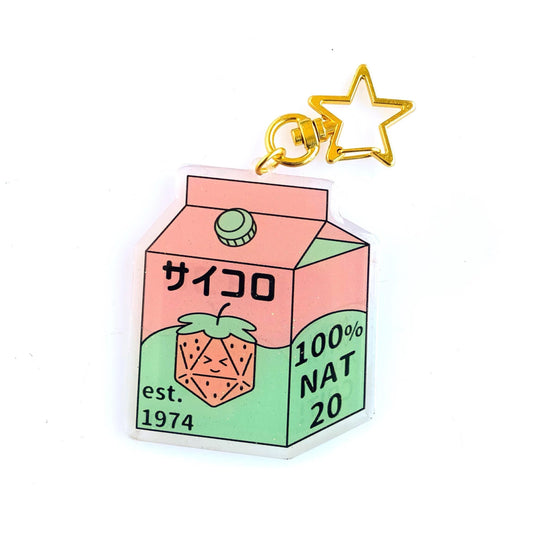 Dice Box Charm — clear acrylic charm shaped like a juice carton with strawberry-d20 art, Japanese サイコロ (saikoro = dice) text, '100% NAT 20' and 'est. 1974'. Pink and sage green palette, gold star keyring. D&D dice charm.