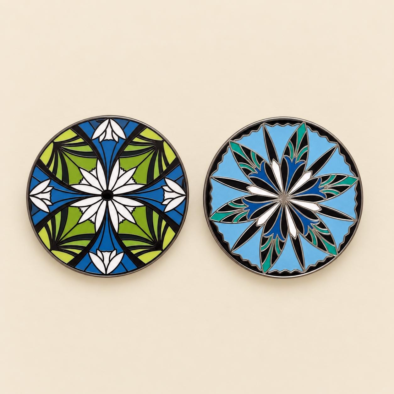 Two round elven flower enamel pins side by side, one green with white flowers, one sky blue with a twelve point star
