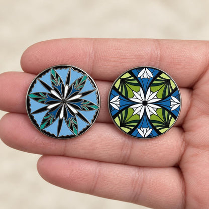 Two elven flower enamel pins resting in an open palm for scale