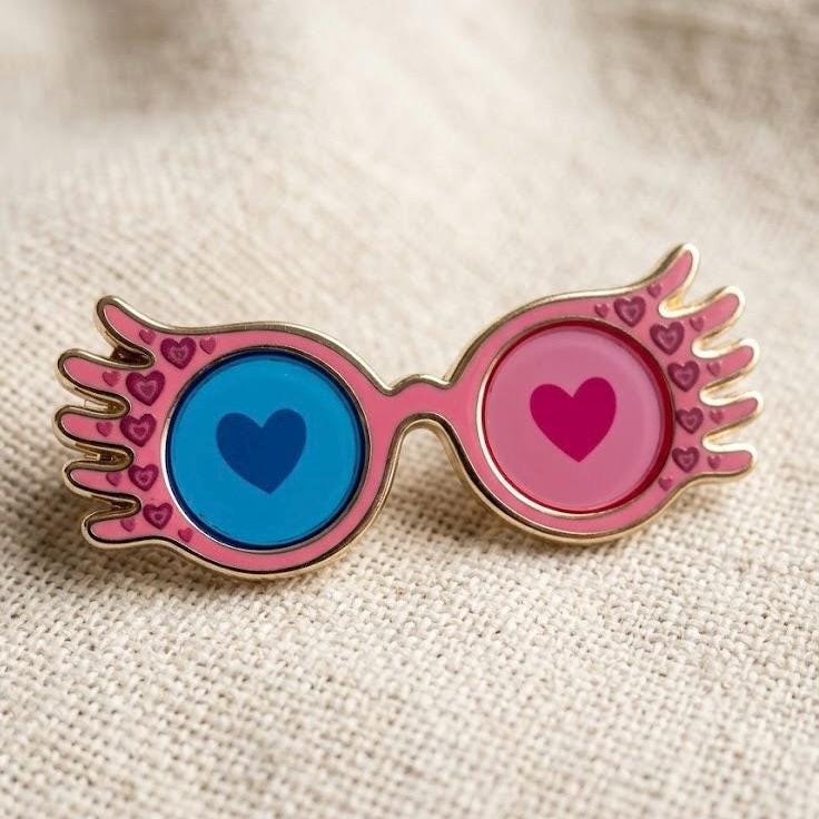 Moonstruck winged heart glasses enamel pin, gold with blue and pink transparent heart lenses