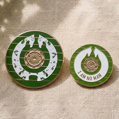 Size comparison: Shieldmaiden's Shield pin beside the smaller Éowyn's Shield I Am No Man pin