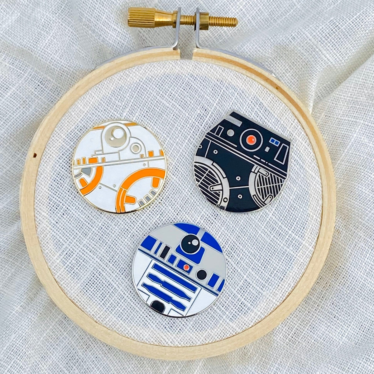 Three little bot needle minders in an embroidery hoop
